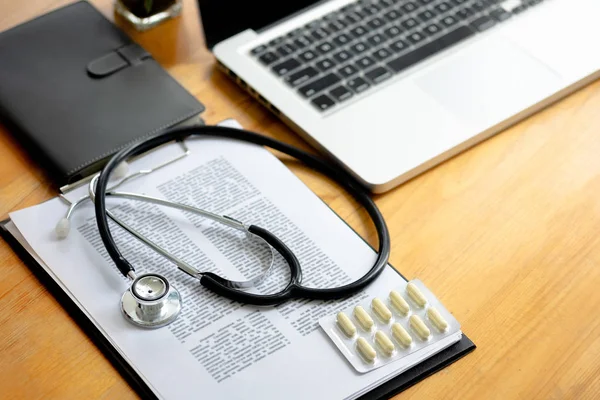 stethoscope in medical clinic with record report documents and laptop.