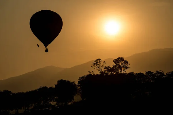 The silhouette of hot air balloon flying up in the sky during sunset view.