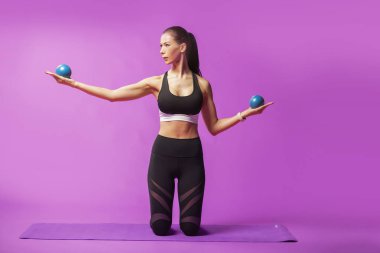 Uzun saçlı güzel pilates ya da yoga atlet bir stüdyoda pembe bir arka plan karşı sıkı spor kıyafeti giymiş süre zarif bir poz mu