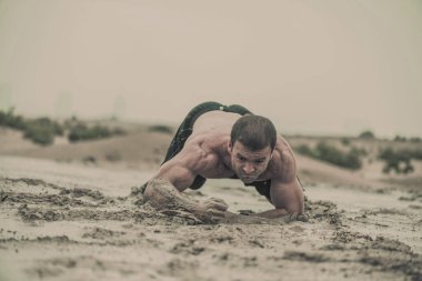 Portre güçlü, kaslı, atletik adamın ıslak, kirli çamurlu su birikintisi bir aşırı rekabetçi spor yağmurda içinde gezinme 
