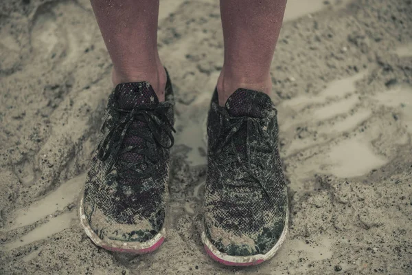 Closeup of muddy  female athletic legs and shoes after running an extreme race in the rain