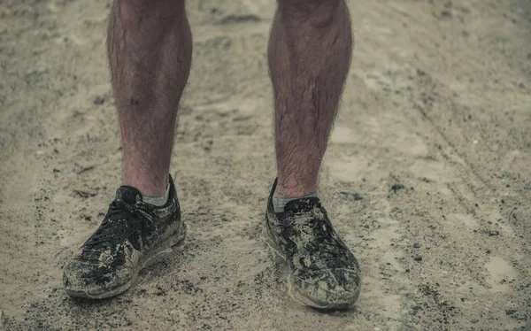 Closeup of hairy, muddy male athletic shoes after running an extreme race in the rain