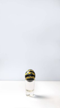 Asgari beyaz arkaplanda siyah ve sarı bir yumurtanın dikey görüntüsü. Modern Paskalya konsepti. Minimalist Paskalya yumurtası dikey. Pysanka sanat modern hikaye şablonu. bayram selamlaması modern tasarım.