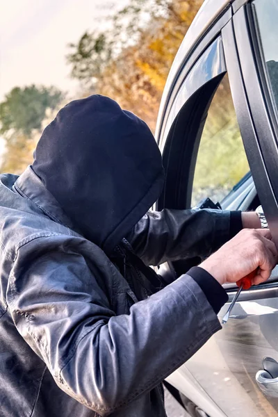 Ladrão usando roupas pretas roubando um carro — Fotografia de Stock