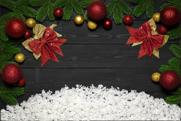 Noel kavramı dekorasyon kar, yay, yeni yıl topları oyuncaklar ile promo ve metin için bir çerçeve ile siyah ahşap zemin çam dalları — Stok fotoğraf