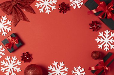 Noel beyaz kar tanesi kırmızı Kağıt arka plan üzerinde kenarlık çerçeve tasarımı ile hediye kutu kırmızı kurdele ve yeni yıl topları ile. Noel dekorasyon üstten görünüm promo metniniz için kopya alanı ile