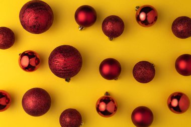 Kırmızı topları ya da oyuncak baubles sarı pastel arka plan üzerinde Noel en az desenle. Düz yatıyordu, en iyi görünümü