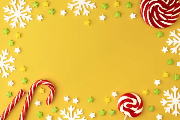 Christmas pattern with Lollipops sweets round copy space. Candy with snowflake, flat lay on yellow pastel  background. Sweet sucker, candy, isolated minimal above decoration, sweet food background — Stock Photo, Image