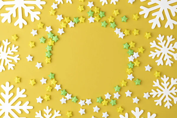 Christmas pattern with Lollipops sweets round copy space. Candy with snowflake, flat lay on yellow pastel  background. Sweet sucker, candy, isolated minimal above decoration, sweet food background