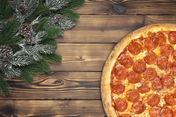 Pizza de Navidad en el tablero de madera con rama de abeto y cono de pino — Foto de Stock