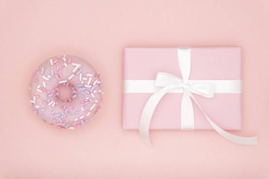 Sevgililer ya da Doğum günü üstten görünüm kompozisyon pembe hediyesi ile tatlı çörek mercan Kağıt arka plan üzerinde beyaz kurdele ile. Kavram dekor aşk gün veya gün. Düz yatıyordu