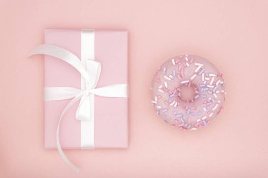 Sevgililer ya da Doğum günü üstten görünüm kompozisyon pembe hediyesi ile tatlı çörek mercan Kağıt arka plan üzerinde beyaz kurdele ile. Kavram dekor aşk gün veya gün. Düz yatıyordu