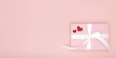 Sevgililer günü fikir kompozisyon: pembe hediye kutusu beyaz kurdele ve kağıt mercan arka plan üzerinde küçük kırmızı kalpler ile. Üstten görünüm. Aşk gün kavramı düz yatıyordu