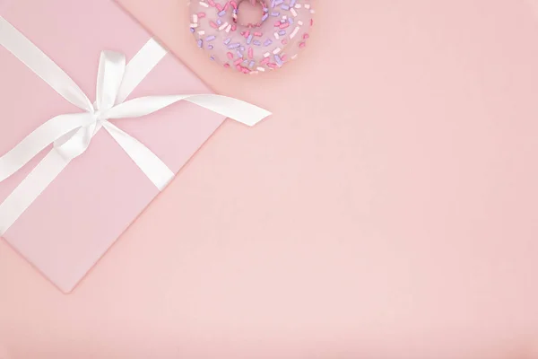 Валентина или день рождения композиция вид сверху розовый подарок с белой лентой со сладким пончиком на коралловом бумажном фоне. Концепция декора день любви или женский день. Плоский лежал. Копирование пространства — стоковое фото