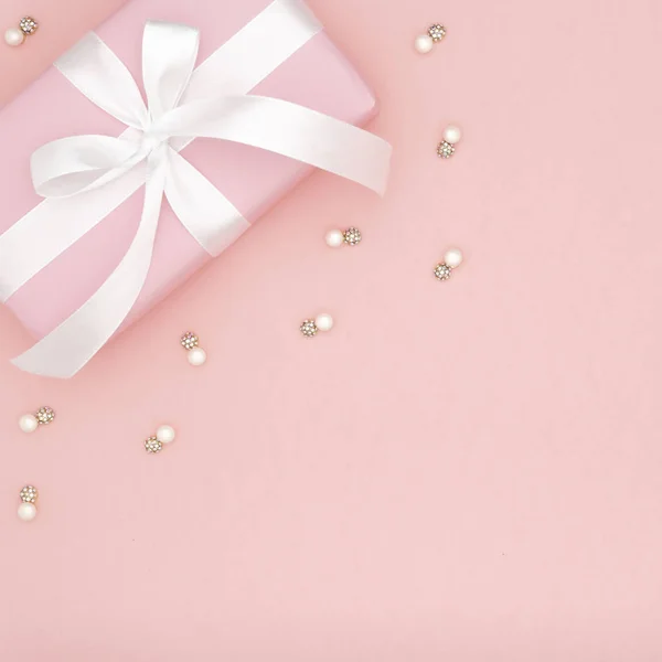 Valentine of vrouwen dag roze geschenk met witte boog lint op koraal papier achtergrond. Begrip inrichting liefde dag of verjaardag. Flat lag. Kopiëren van ruimte — Stockfoto