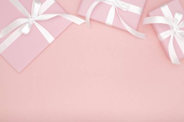 Mercan Kağıt arka plan üzerinde beyaz yay kurdele ile Sevgililer ya da kadınlar günü pembe hediyesi. Kavram dekor aşk gün veya Doğum günü. Düz yatıyordu. Kopya alanı.