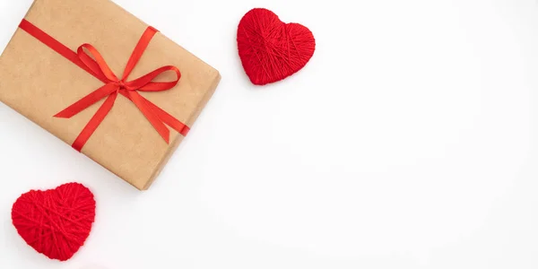 Caja de regalo de papel artesanal de San Valentín o mujer con cinta de lazo roja decorada con pequeños corazones rojos vista superior sobre fondo blanco. Decoración conceptual caja de regalo para el día del amor o cumpleaños. Acostado. Copiar espacio — Foto de Stock