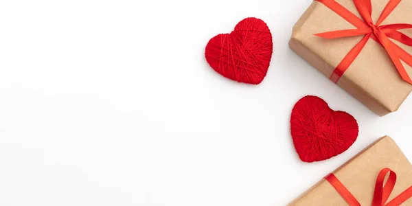 Día de San Valentín decoración en mesa escritorio vista superior. Composición plana de forma roja corazón y caja de regalo de papel artesanal con cinta de lazo rojo fondo blanco para maqueta de su diseño. Concepto de día de amor — Foto de Stock