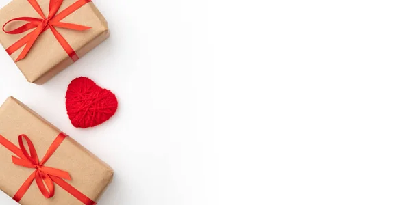 Caja de regalo de papel artesanal de San Valentín o mujer con cinta de lazo roja decorada con una pequeña vista superior roja del corazón sobre un fondo blanco. Decoración conceptual día de amor o cumpleaños. Acostado. Copiar espacio — Foto de Stock