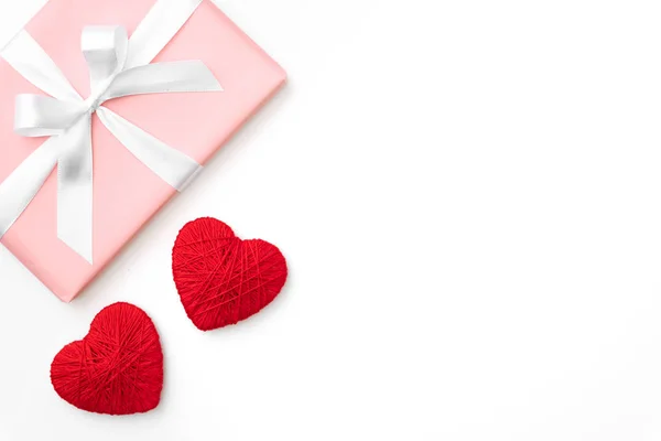 Composição da ideia do dia dos namorados: caixa de presente rosa ou coral com fita branca e pequenos corações vermelhos no fundo branco. Vista superior. Dia de amor conceito flat lay — Fotografia de Stock