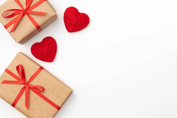 Caja de regalo de papel artesanal de San Valentín o mujer con cinta de lazo roja decorada con una pequeña vista superior roja del corazón sobre un fondo blanco. Decoración conceptual día de amor o cumpleaños. Acostado. Copiar espacio — Foto de Stock
