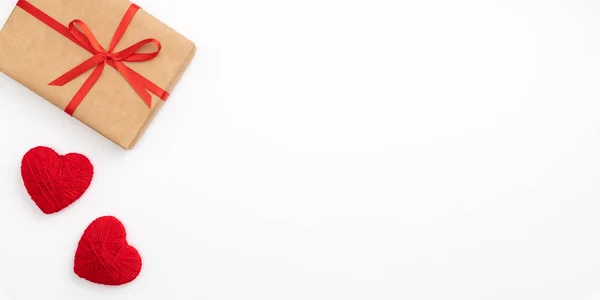 Día de San Valentín decoración en mesa escritorio vista superior con caja actual. Composición plana de corazón rojo y caja de regalo de papel artesanal con cinta de lazo rojo aislado fondo blanco. Concepto de día de amor — Foto de Stock