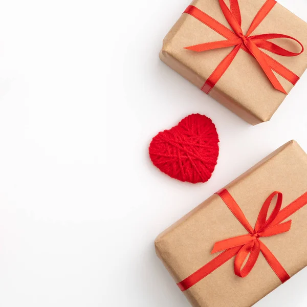 Día de San Valentín decoración en mesa escritorio vista superior. Composición plana de corazón rojo y caja de regalo de papel artesanal con cinta de lazo rojo aislado fondo blanco. Concepto de día de amor — Foto de Stock