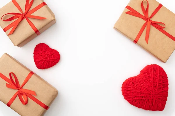 Día de San Valentín decoración en mesa escritorio vista superior. Composición plana de corazón rojo y caja de regalo de papel artesanal con cinta de lazo rojo aislado fondo blanco. Concepto de día de amor — Foto de Stock