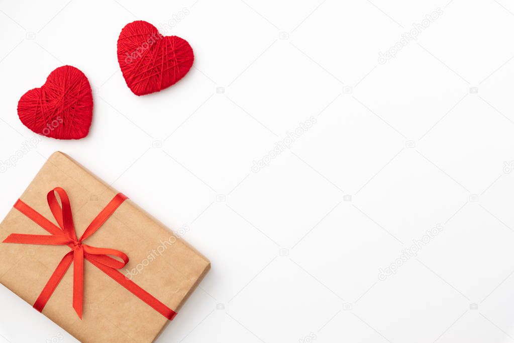 Present box of craft paper with red bow and ribbon top view for Valentines day isolated on white background. Flat lay. Copy space. Gifts box composition for 8 march Womens day, Mothers day