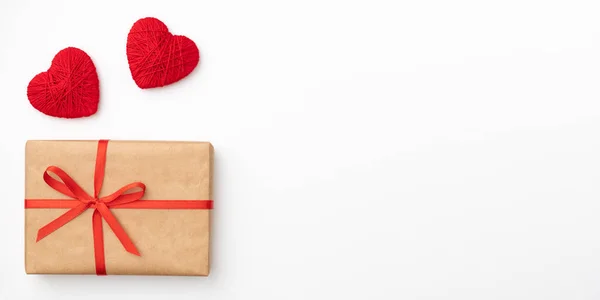 Caixa de presente de papel artesanal com arco vermelho e vista superior da fita para o dia dos namorados isolado no fundo branco. Deitado. Espaço de cópia — Fotografia de Stock