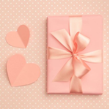 Sevgililer günü fikir kompozisyon: pembe veya mercan hediye kutusu şerit ve üzerinde yaşayan küçük kalpleri ile mercan arka plan. Üstten görünüm. Düz yatıyordu