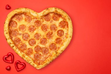 Kalp düz şeklinde pizza kopya alanı Sevgililer günü ile kırmızı arka plan üzerinde yatıyordu.