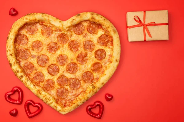 Pizza tvaru srdce pizza salámek na Valentýna s krabičky na červené papírové pozadí — Stock fotografie