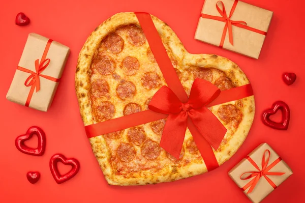 Pizza ve tvaru srdce s červenou mašlí pásu a krabičce pro den svatého Valentýna romantická koncepce na červeném pozadí — Stock fotografie