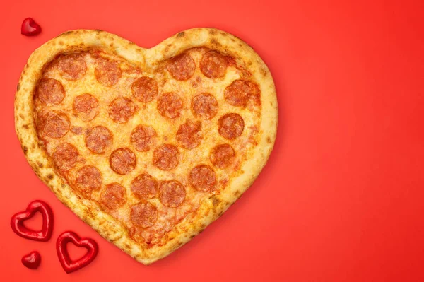 Pizza shaped heart flat lay with copy space Valentine 's Day on red background — стоковое фото