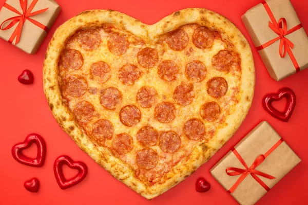 Pizza tvaru srdce pizza salámek na Valentýna s krabičky na červené papírové pozadí — Stock fotografie