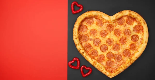 Pizza shaped heart top view Valentine 's Day on black and red background — стоковое фото