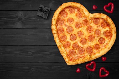 Pizza kalp rustik koyu siyah arka plan üzerinde kopya alanı ile Sevgililer günü için. Üstten görünüm. Düz yatıyordu.