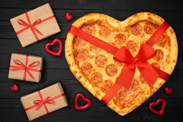 Pizza ve tvaru srdce s červenou mašlí pásu a krabičce pro den svatého Valentýna romantická koncepce na rustikální tmavé černé pozadí. Pohled shora. Rozložení bytu — Stock fotografie