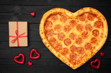 Pizza kalp için Sevgililer günü romantik kavramı kopya alanı rustik koyu siyah arka plan üzerine. Üstten görünüm. Düz yatıyordu
