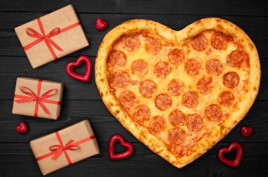 Pizza hediye kutusu rustik koyu siyah arka plan üzerinde romantik kavramı Sevgililer günü için kalp şeklinde. Üstten görünüm. Düz yatıyordu