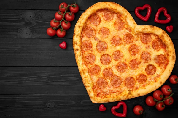 Pizza pepperoni shaped heart for Valentine 's Day with copy space on rustic dark black background. Вид сверху. Плоский лежал — стоковое фото