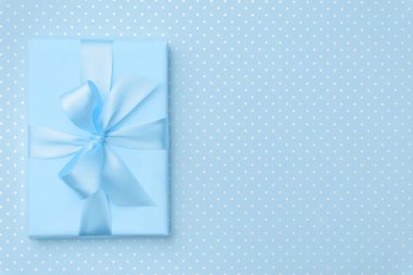 Hediye kutusu ile mavi arka plan üstten görünüm mavi şerit yay. Xmas tatil tatil kavramı, Doğum günü hediyesi, yeni yıl veya Noel hediye kutusu sunar. Tebrikler kopya alanı ile. Düz Lay.