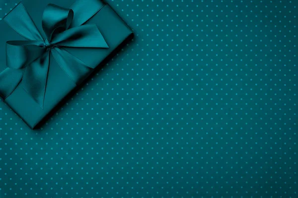Gift box with green ribbon on dark turquoise speckled background top view. Holiday concept, birthday gift, 8 march or Women day, blue gift box holiday Mothers day. Copy space. Flat Lay