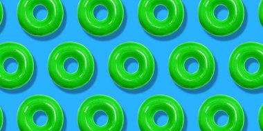 Yaratıcı desen yeşil çörekler düz pastel mavi arka plan üzerinde yatıyordu. Minimal tatlı gıda konsepti. Fırın için gerçeküstü donut kek üst görünümü. Soyut yaz çörek tatlısı