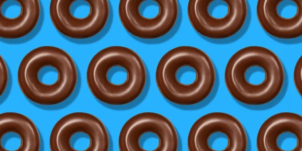 Творческий узор шоколадного пончика лежал на голубом фоне. Минимальная концепция сладкой пищи. Surreal brown donghnuts cake top view for bakery. Абстрактный летний пончик — стоковое фото