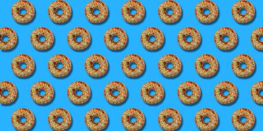 Yaratıcı desen Donuts renkli düz pastel mavi arka planda yatıyordu. Minimal tatlı gıda kavramı. Ekmek için gerçeküstü donut kek üst görünümü. Soyut yaz donut tatlı