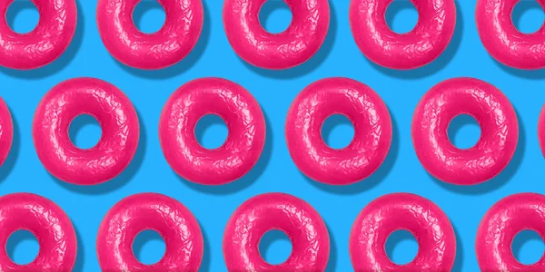 Yaratıcı desen pembe Donuts düz pastel mavi arka planda yatıyordu. Minimal tatlı gıda kavramı. Ekmek için gerçeküstü donut kek üst görünümü. Soyut yaz donut tatlı
