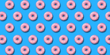 Yaratıcı desen pembe Donuts düz pastel mavi arka planda yatıyordu. Minimal tatlı gıda kavramı. Ekmek için gerçeküstü donut kek üst görünümü. Soyut yaz donut tatlı
