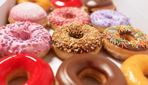 Closeup assorted donuts with different fillings in box for pastry delivery on white background. Sweet fast food concept. Tasty dessert doughnuts cake from bakery of breakfast. Donut macro collection